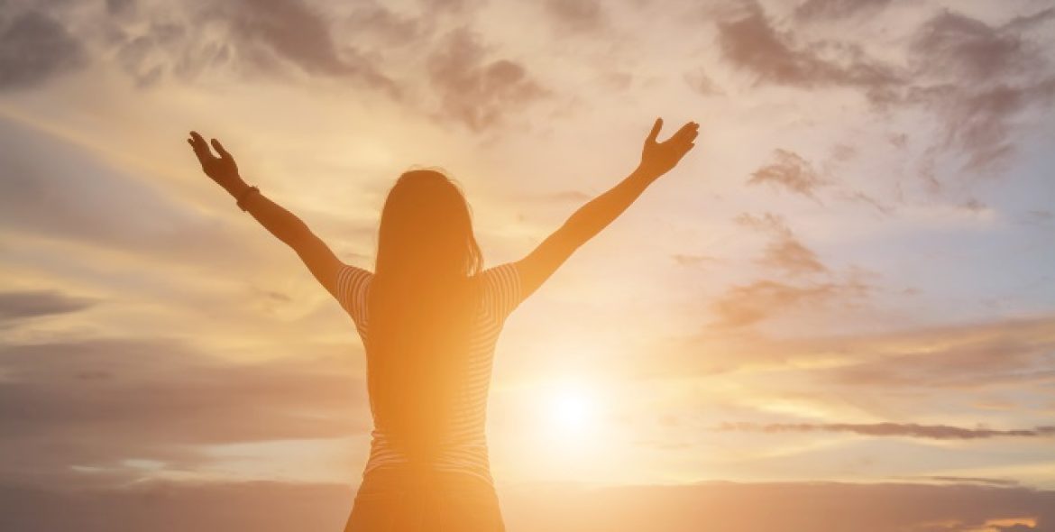 Silhouette of woman praying over beautiful sky background